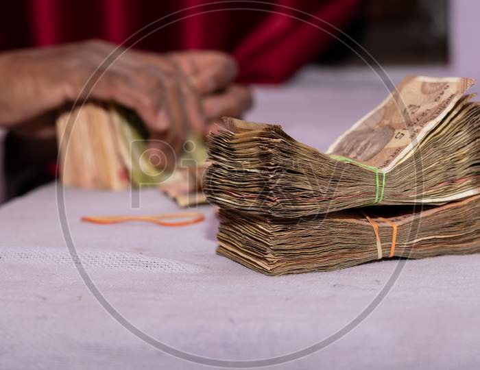 A man counting Indian currency notes put on table