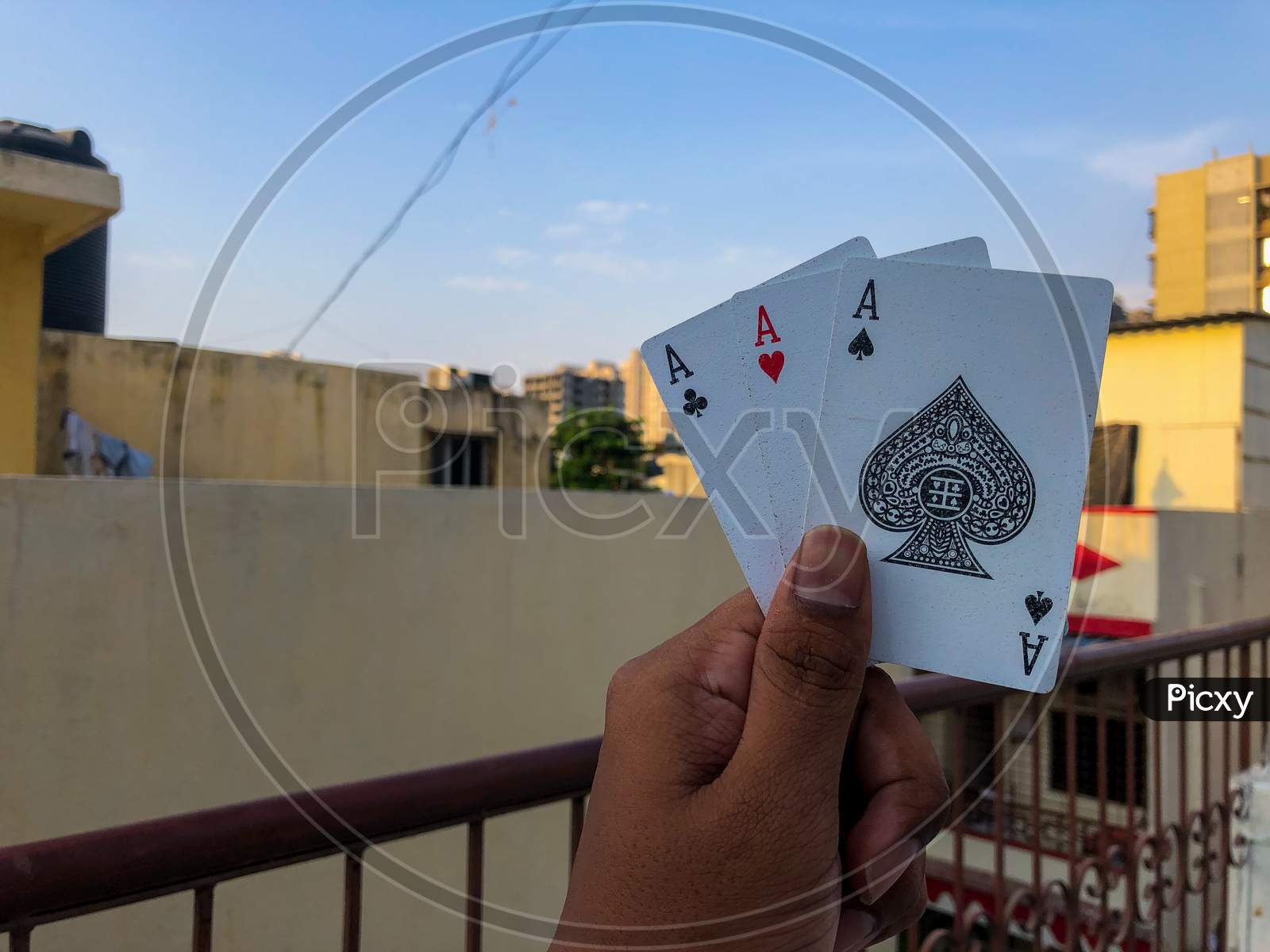 poker playing cards in hand with corporate background and blue sky