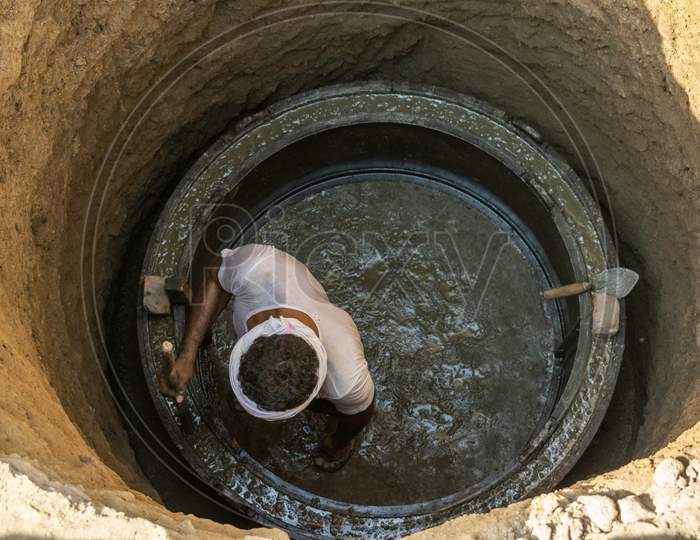 A man adjusts concrete in a mould during construction of a septic tank