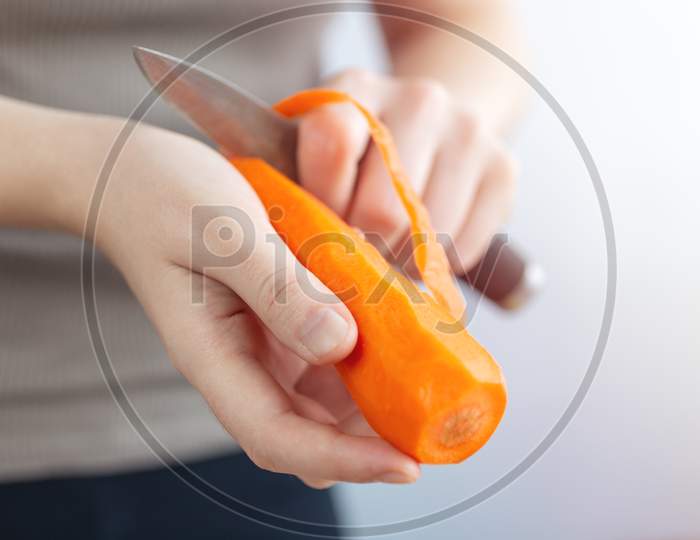 Close up of hands peeling cutting orange carrot with a knife. Healthy food preparation concept Close up of hands peeling cutting orange carrot with a knife. Healthy food preparation concept