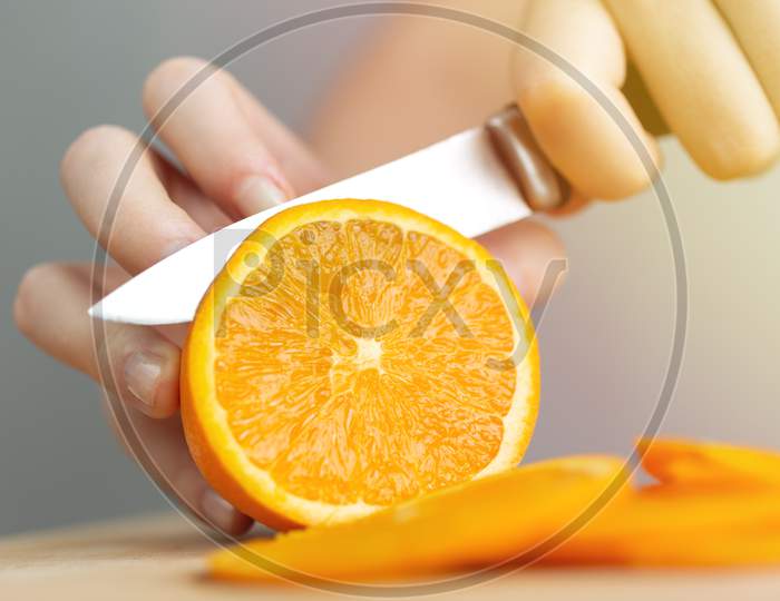 Close up hands cutting a ripe juicy orange with a knife. Healthy fruit food preparation concept