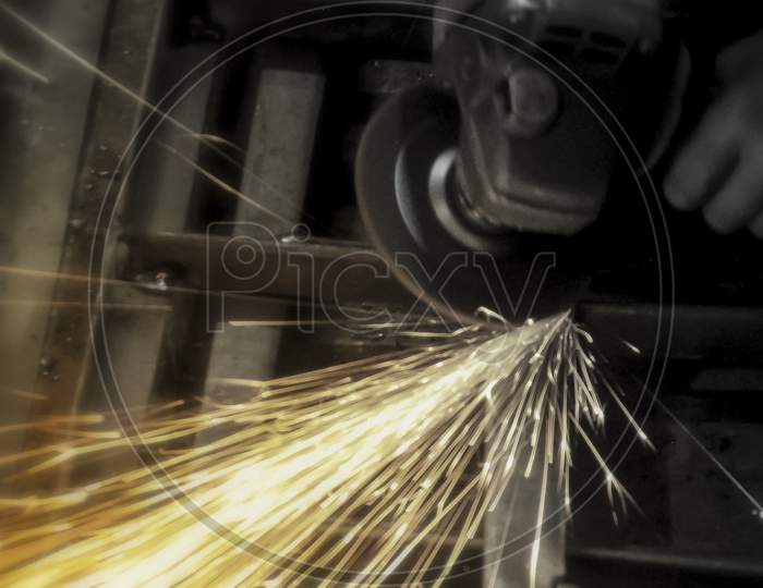 Close-Up Of Worker Cutting Metal With Grinder. Sparks While Grinding Iron. Industry, Selective Focus.