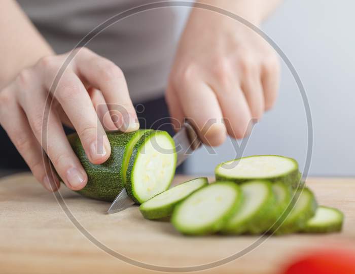 Close up of green zucchini cucumber cutting with a knife. Healthy food preparation concept