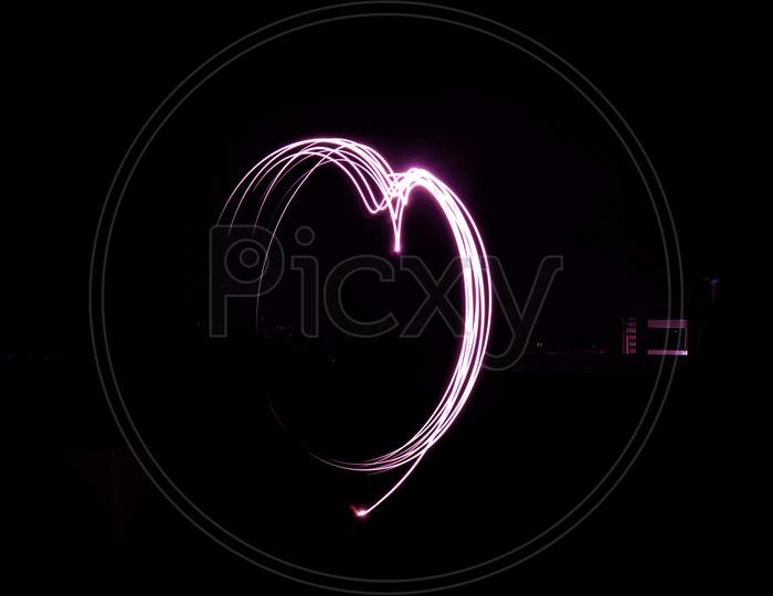 Pink half heart sign in black background, low shutter speed Photography