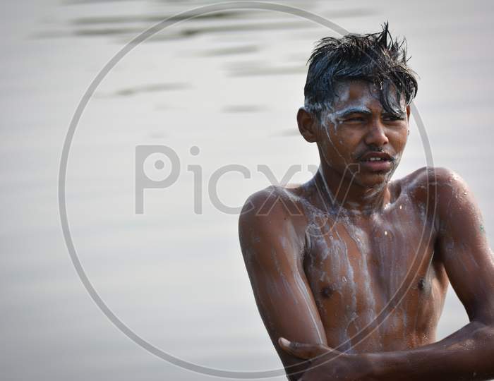 TIKAMGARH, MADHYA PRADESH, INDIA - NOVEMBER 13, 2019: Indian village boy bathing in the river on morning, Washing body and hair with shampoo.