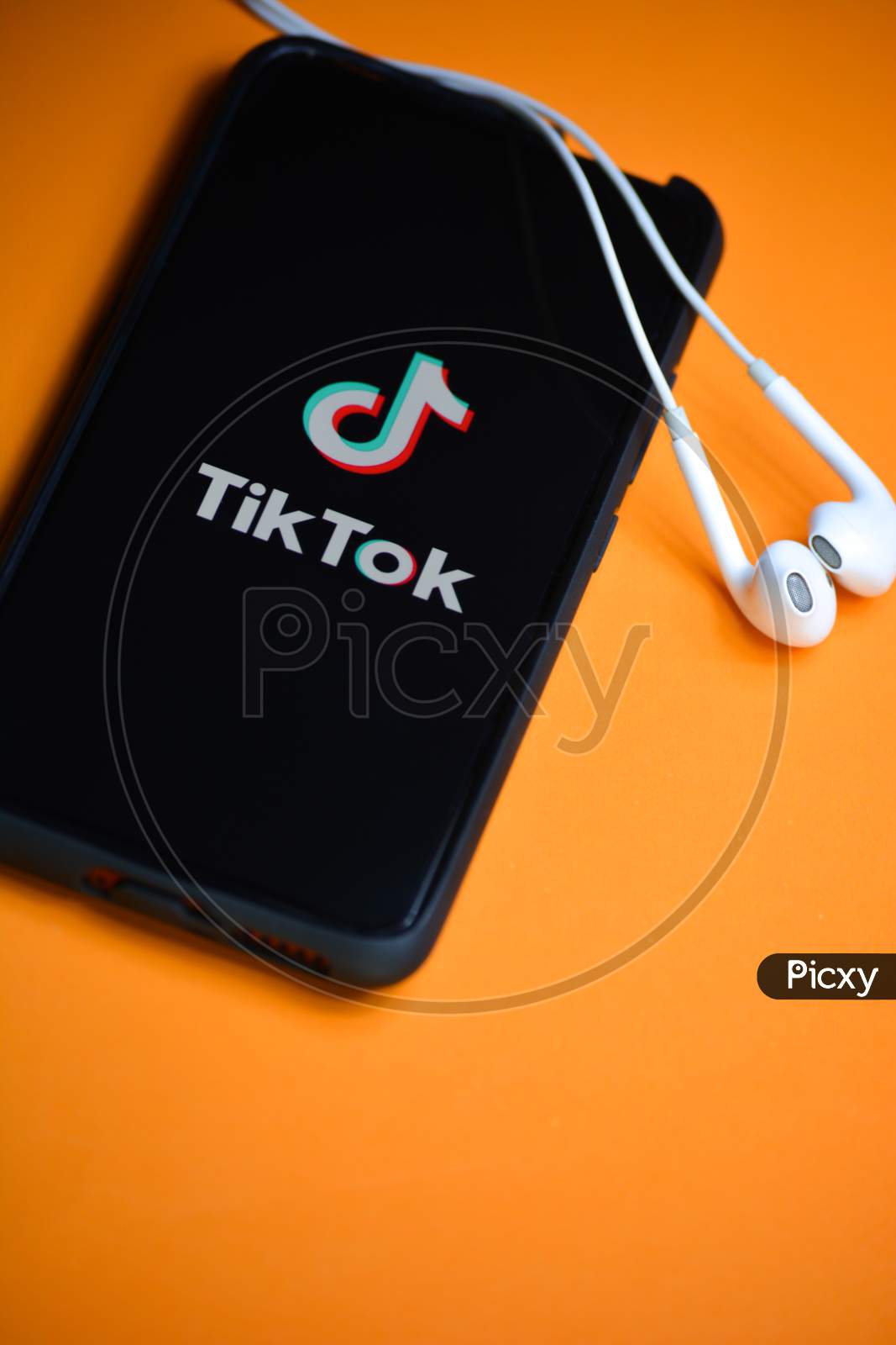 TIKAMGARH, MADHYA PRADESH, INDIA - DECEMBER 17, 2019: Tik Tok application icon on mobile phone screen with earphones. Tik Tok is app to create and share videos
