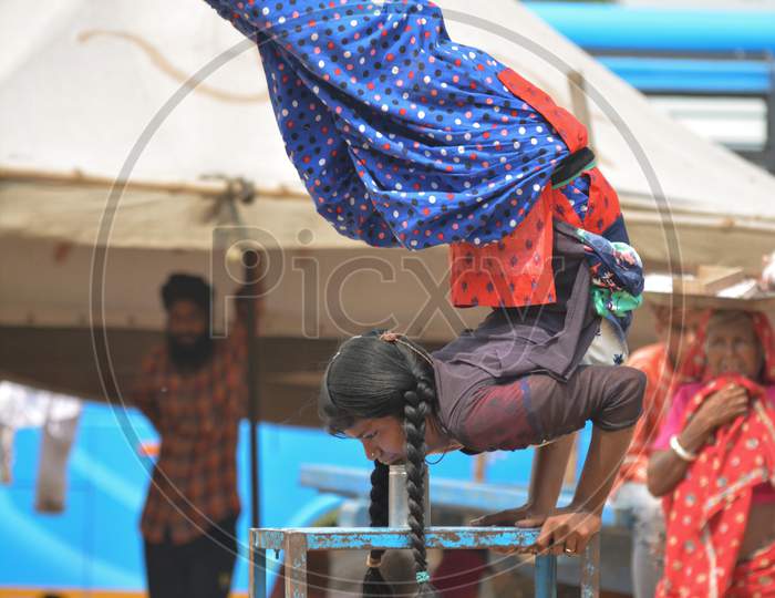 Girl Balancing on bench with head down and feet up in the air Performing Balancing Trick In Public For Earning Money