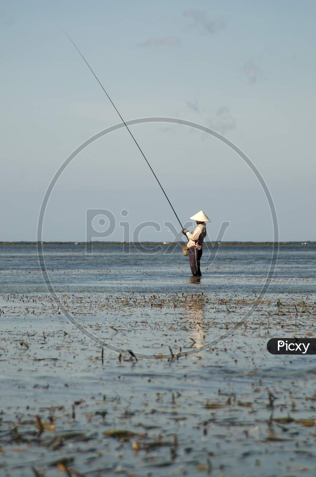 Typical Balinese Fisherman Standing In Shallow Water