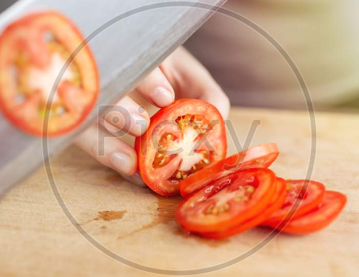 Close up of red ripe tomato cutting with a knife. Healthy food preparation concept