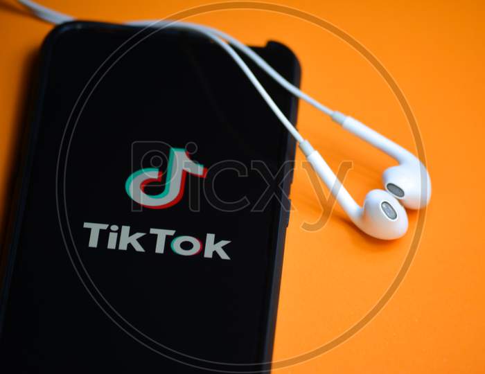 TIKAMGARH, MADHYA PRADESH, INDIA - DECEMBER 17, 2019: Tik Tok application icon on mobile phone screen with earphones. Tik Tok is app to create and share videos