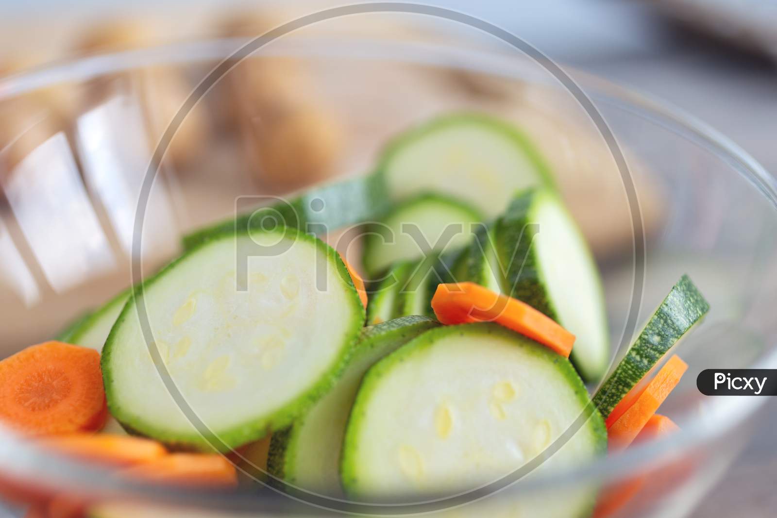 Close up of green zucchini cucumber and carrot slices in a bowl. Healthy food preparation concept
