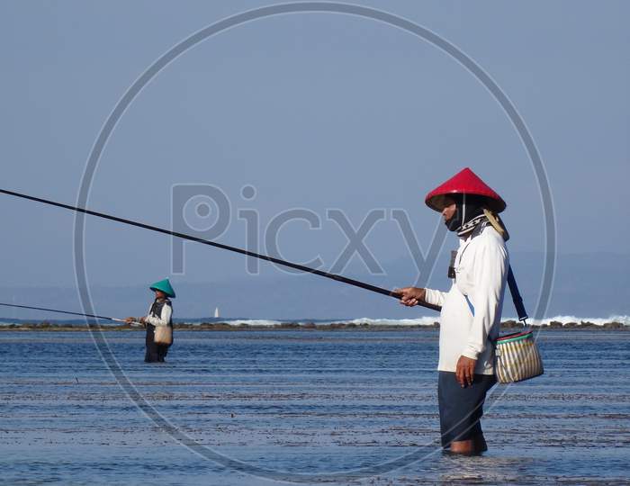 Typical Balinese Fishermen Standing In Shallow Water