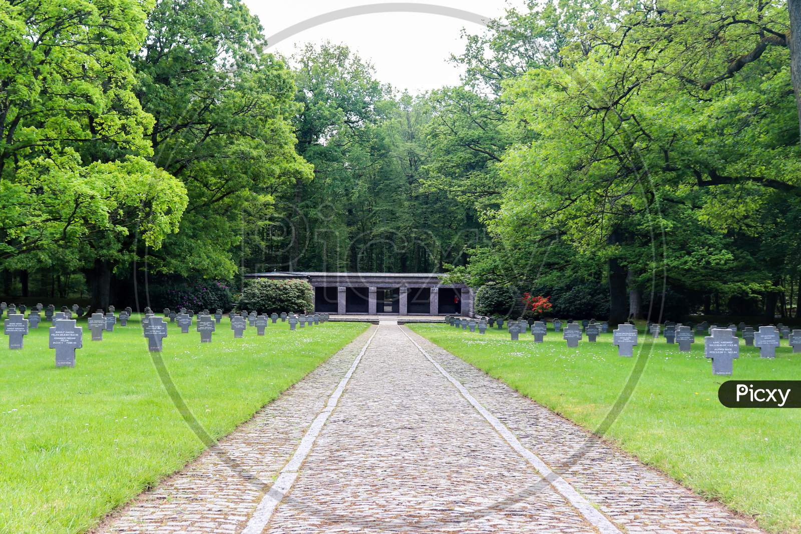 Sandweiler, Luxembourg - May 26, 2019: Path leading to the entrance at the Sandweiler German War Cemetery with graves on either side.