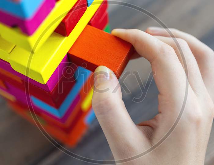 Close up of a hand pulling a colorful   block from a big pile. Fun board games concept