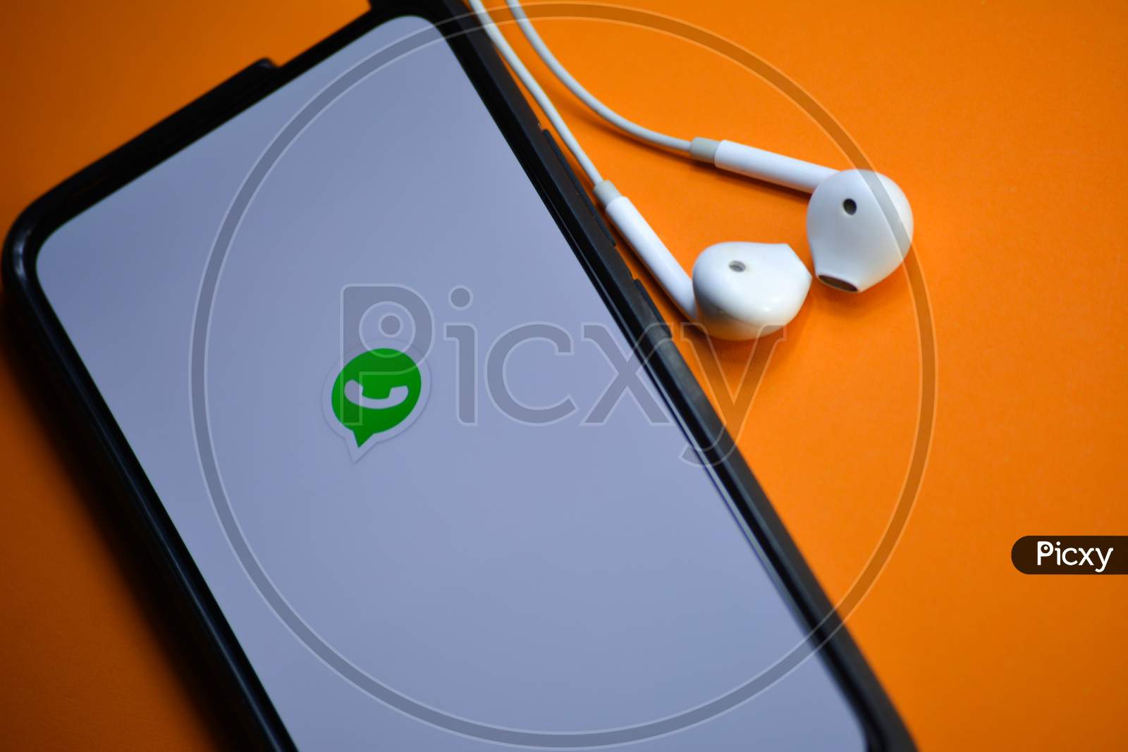TIKAMGARH, MADHYA PRADESH, INDIA - DECEMBER 17, 2019: WhatsApp logo on smartphone screen with earphones. WhatsApp is an online instant messaging service