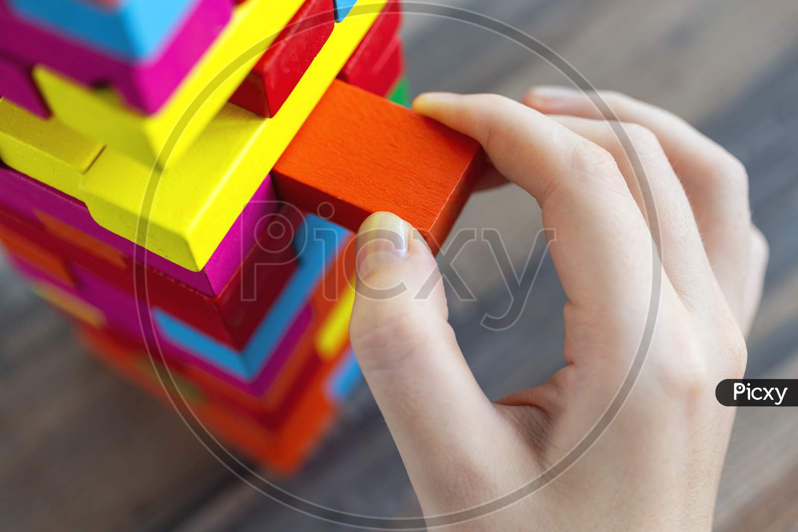 Close up of a hand pulling a colorful   block from a big pile. Fun board games concept