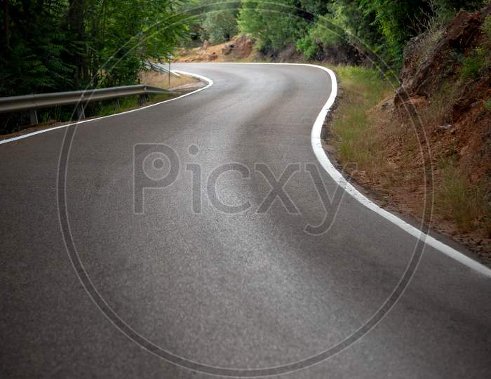 Curved Road In The Forest With White Lines