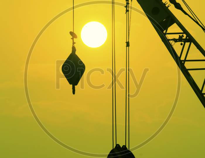 Industrial Construction Cranes And Building Silhouettes Over Sun At Sunrise.
