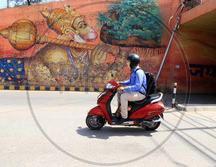 An Office Commuter Drives Past A Mural of Lord Hanuman In Prayagraj