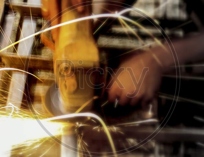 Close-Up Of Worker Cutting Metal With Grinder. Sparks While Grinding Iron. Industry, Soft Selective Focus.