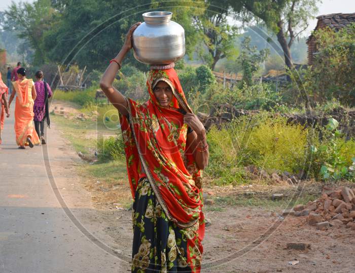 TIKAMGARH, MADHYA PRADESH, INDIA - NOVEMBER 12, 2019: An unidentified indian village woman carry water on their heads in traditional pots from well, An Indian rural scene.