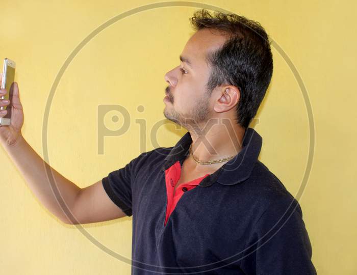 Young handsome Indian man taking selfie with mobile phone