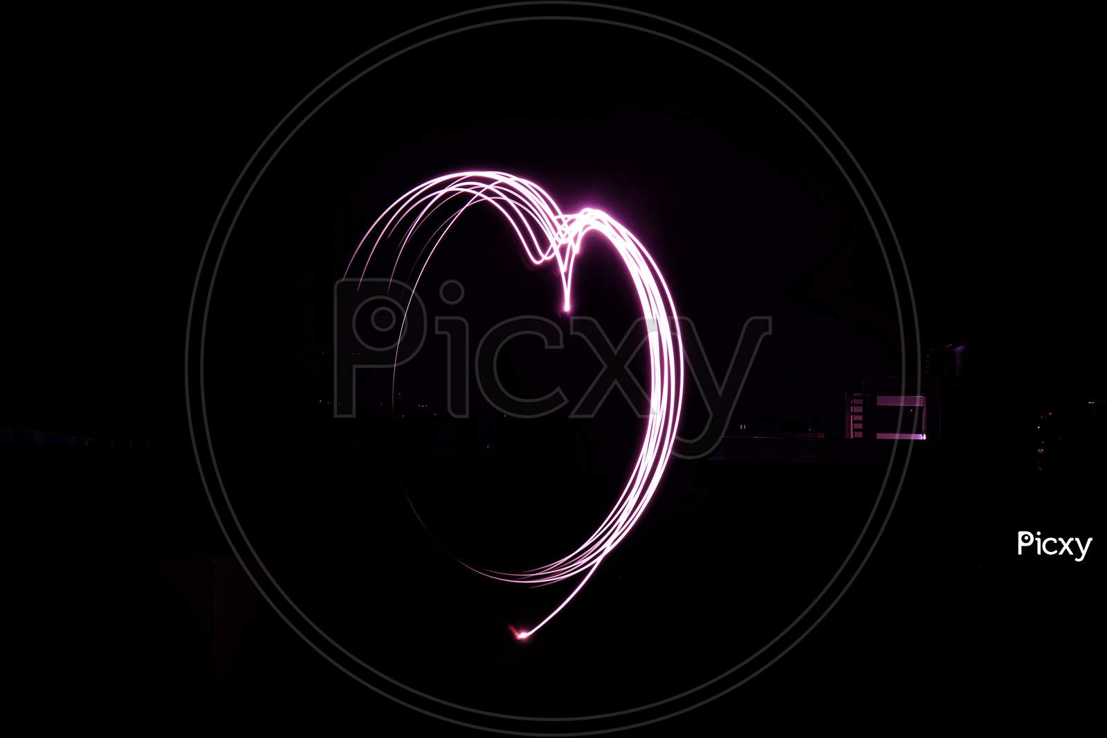 Pink half heart sign in black background, low shutter speed Photography