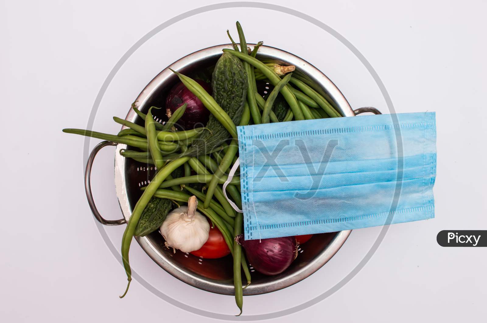 Mask placed on a vegetable basket on white background
