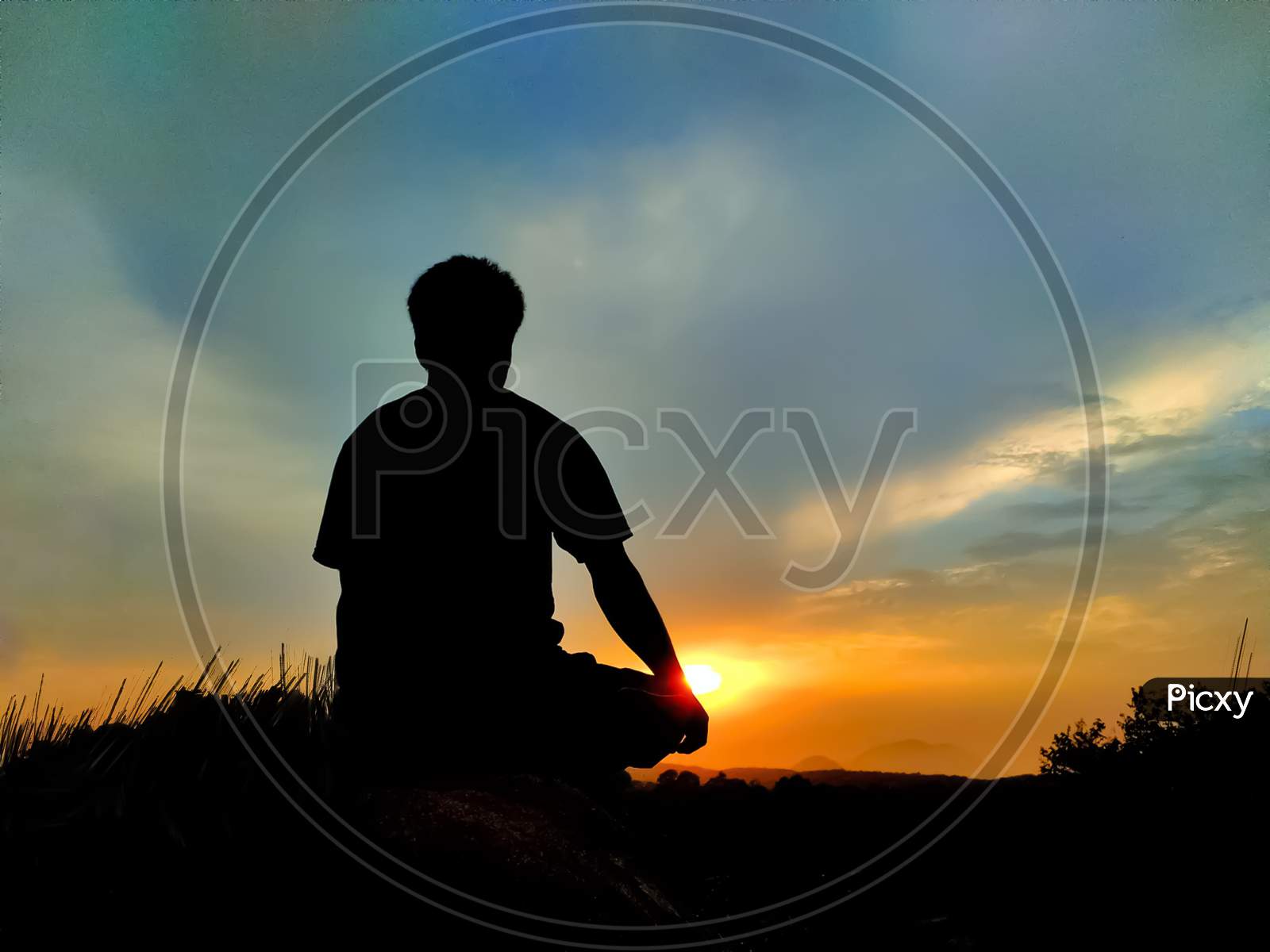 A man sitting on a hill and enjoy the sunset
