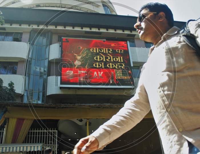 A man walks past a screen displaying the current market situation amid coronavirus outbreak, on the facade of the Bombay Stock Exchange (BSE) , in Mumbai, India, on March 12, 2020.