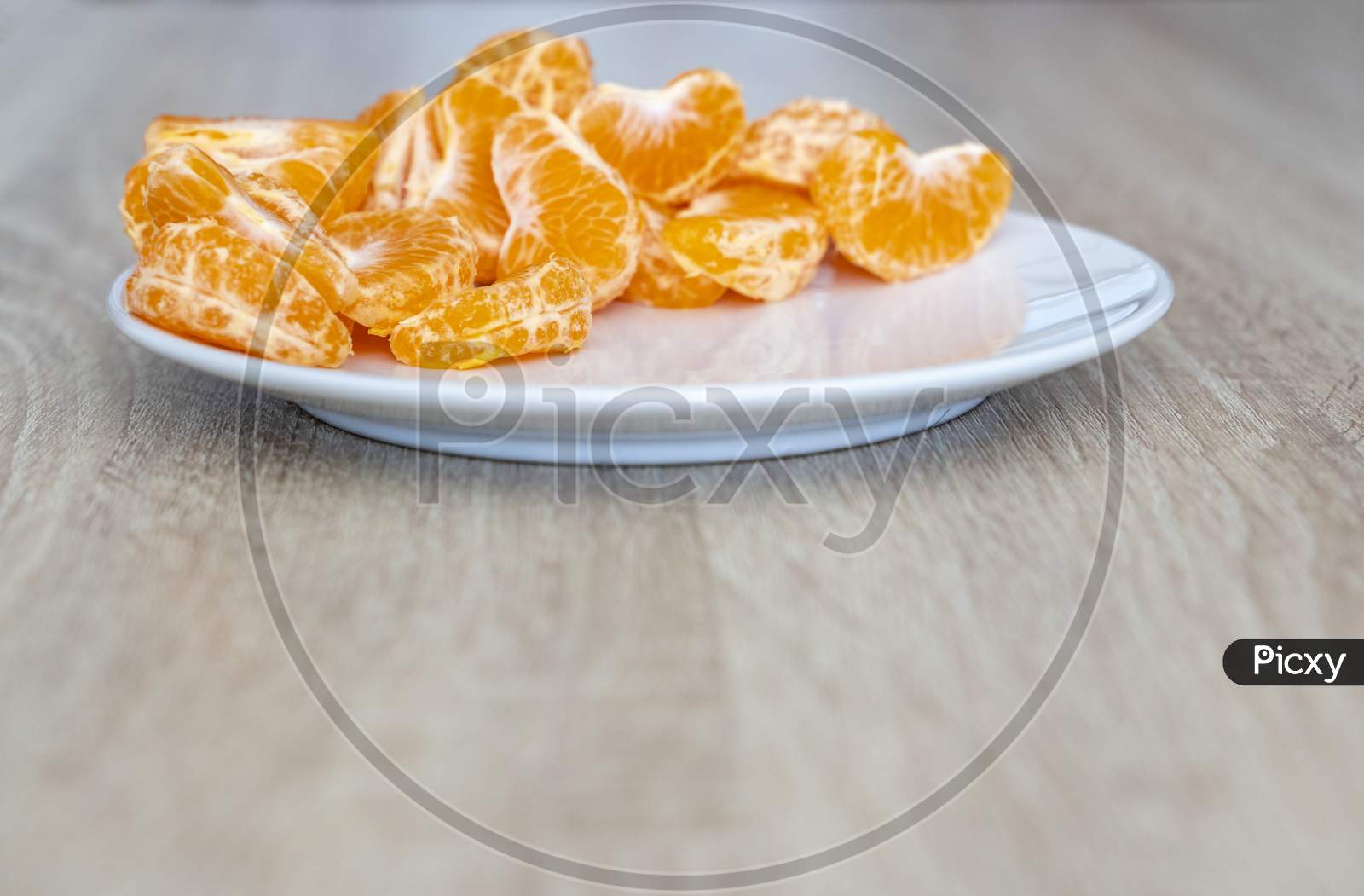 Pealed Mandarin Peaces On White Plate, Wooden Desk Surface