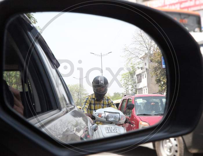 A Person on Scooty in a Car Side Mirror