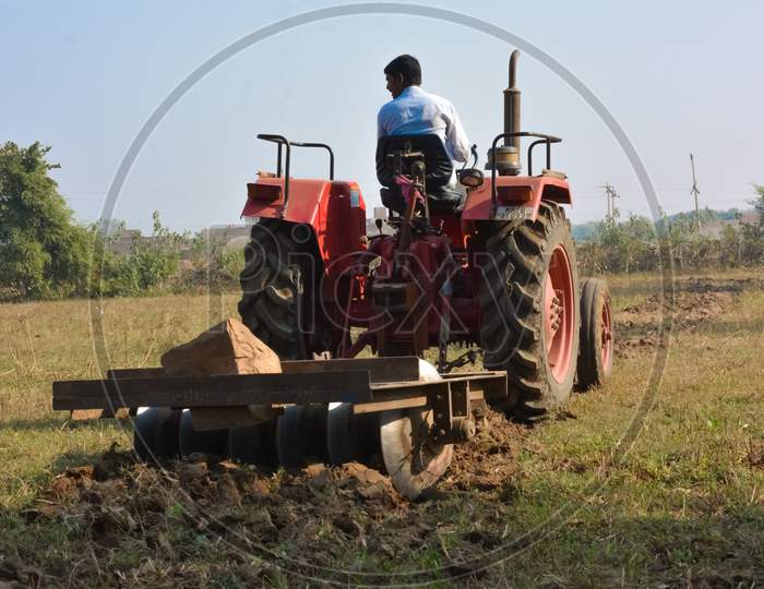 TIKAMGARH, MADHYA PRADESH, INDIA - NOVEMBER 10, 2019: Indian farmer with tractor preparing land for sowing with harrow.