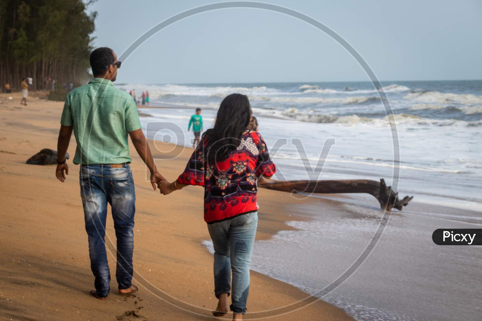 Couple Walking On Sandy Beach With Holding Each Others Hand And Soaking Up The Natural Sea View
