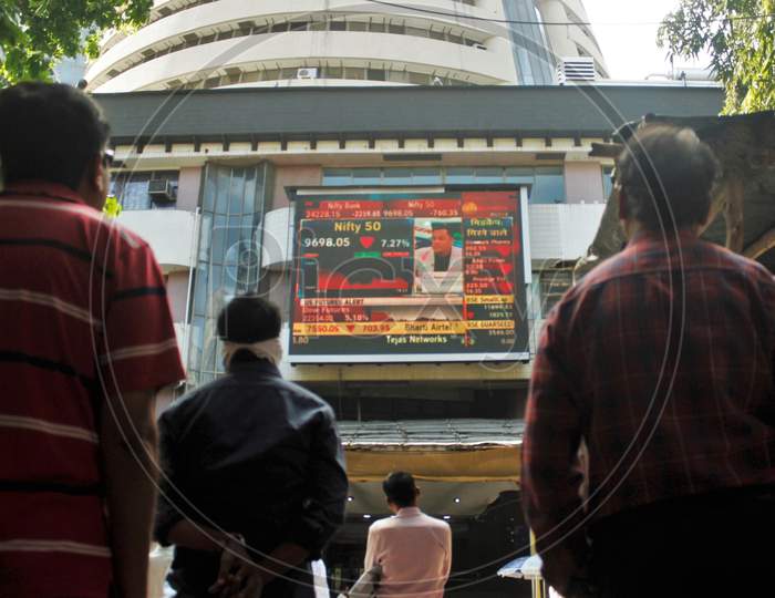 People look at a screen displaying the Sensex results following the coronavirus outbreak, on the facade of the Bombay Stock Exchange (BSE) building in Mumbai, India on March 12, 2020.