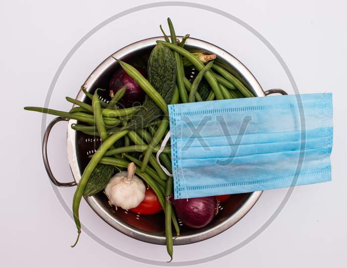 Mask placed on a vegetable basket on white background