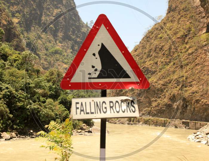 Falling Rocks Sign Board with Mountains in the Background