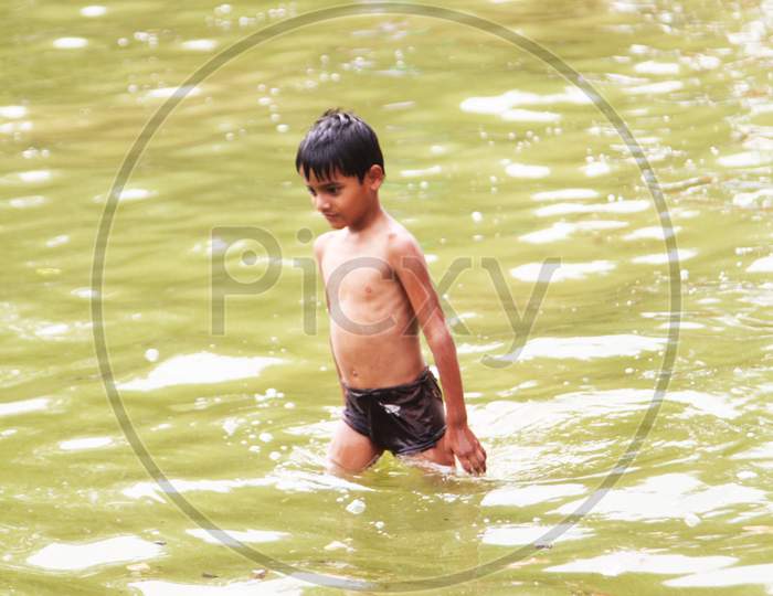 A Kid walking in a water Pond