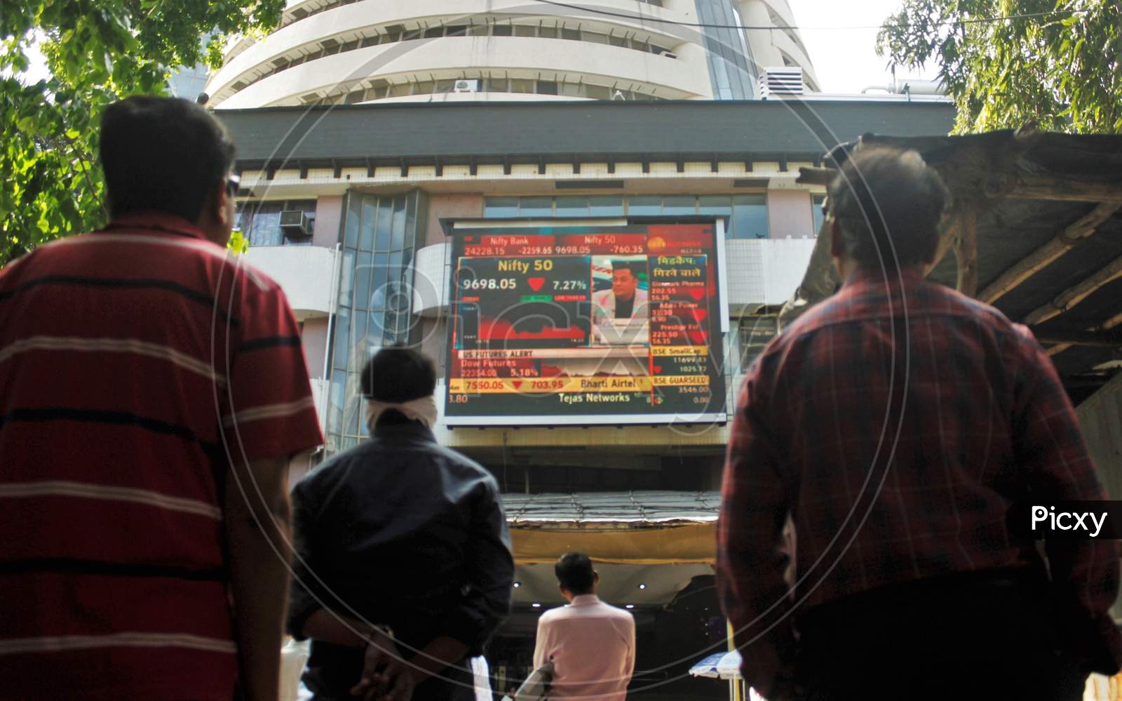 People look at a screen displaying the Sensex results following the coronavirus outbreak, on the facade of the Bombay Stock Exchange (BSE) building in Mumbai, India on March 12, 2020.