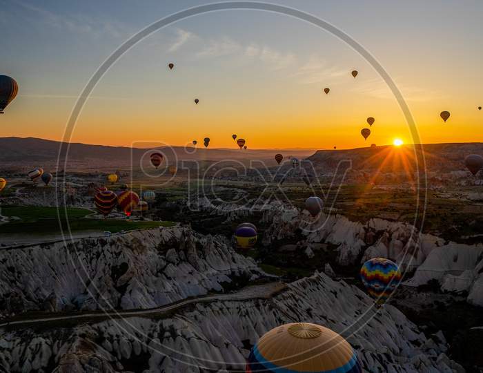 Amazing view of sunset with colorful hot air balloons in sky