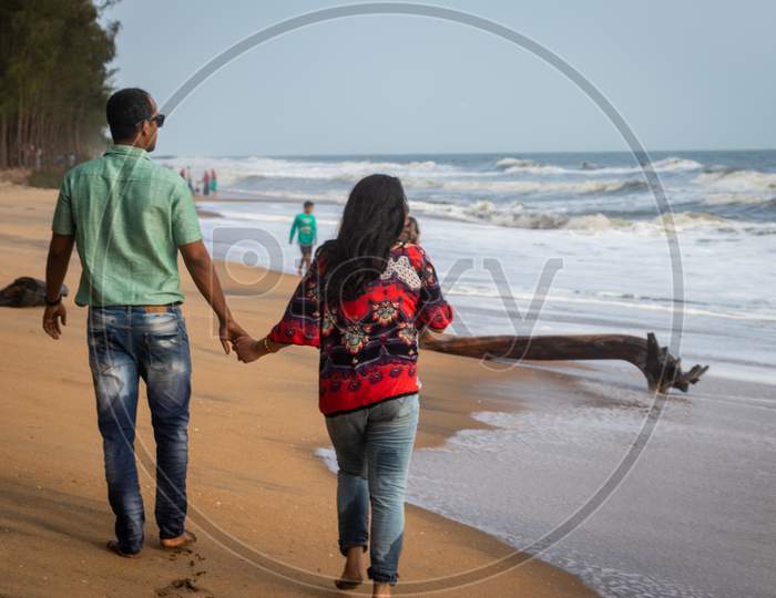 Couple Walking On Sandy Beach With Holding Each Others Hand And Soaking Up The Natural Sea View