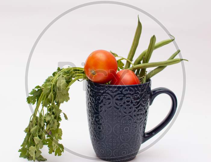 Vegetables and fruit in a blue mug on white background
