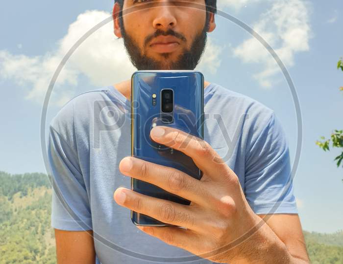 A young Indian man takes photo of himself in front of a mirror with sensor / Lens dust