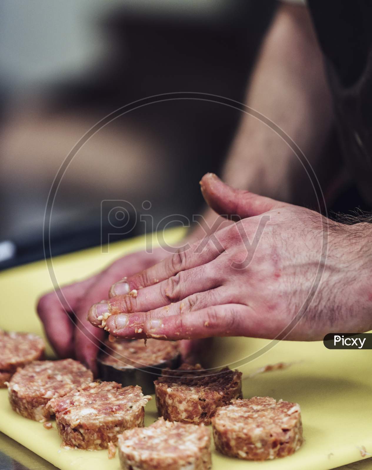 Male Chef Hands Making Round Pork Cutlets On Yellow Cutting Board