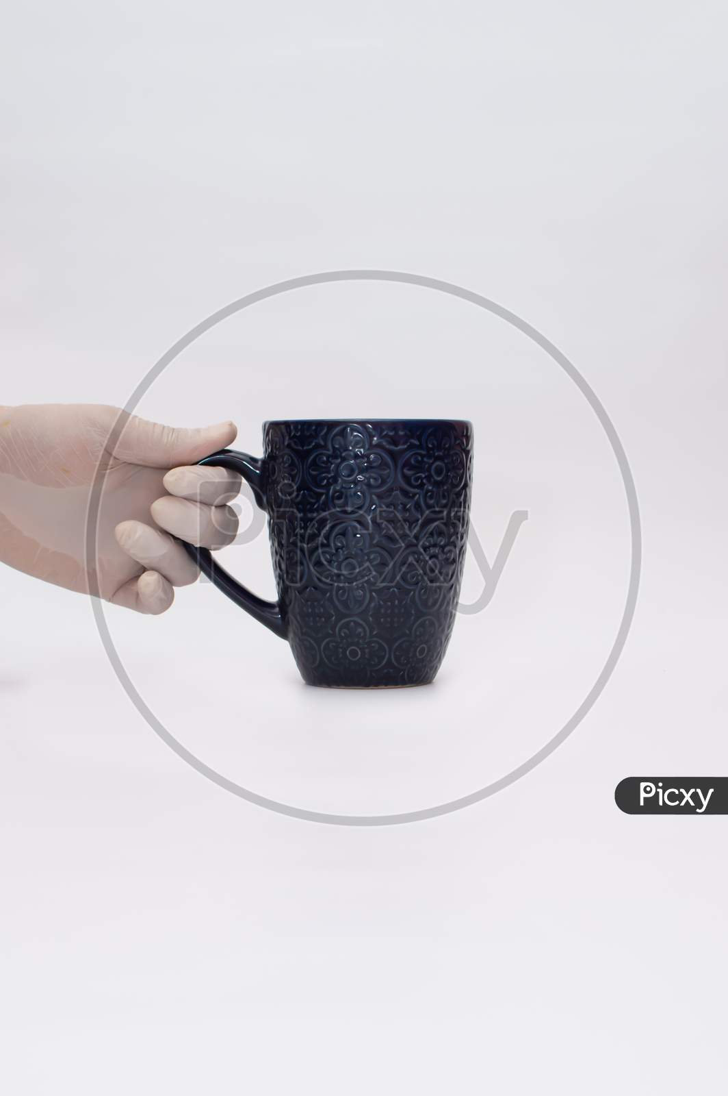 Hand with gloves holding handle of a mug