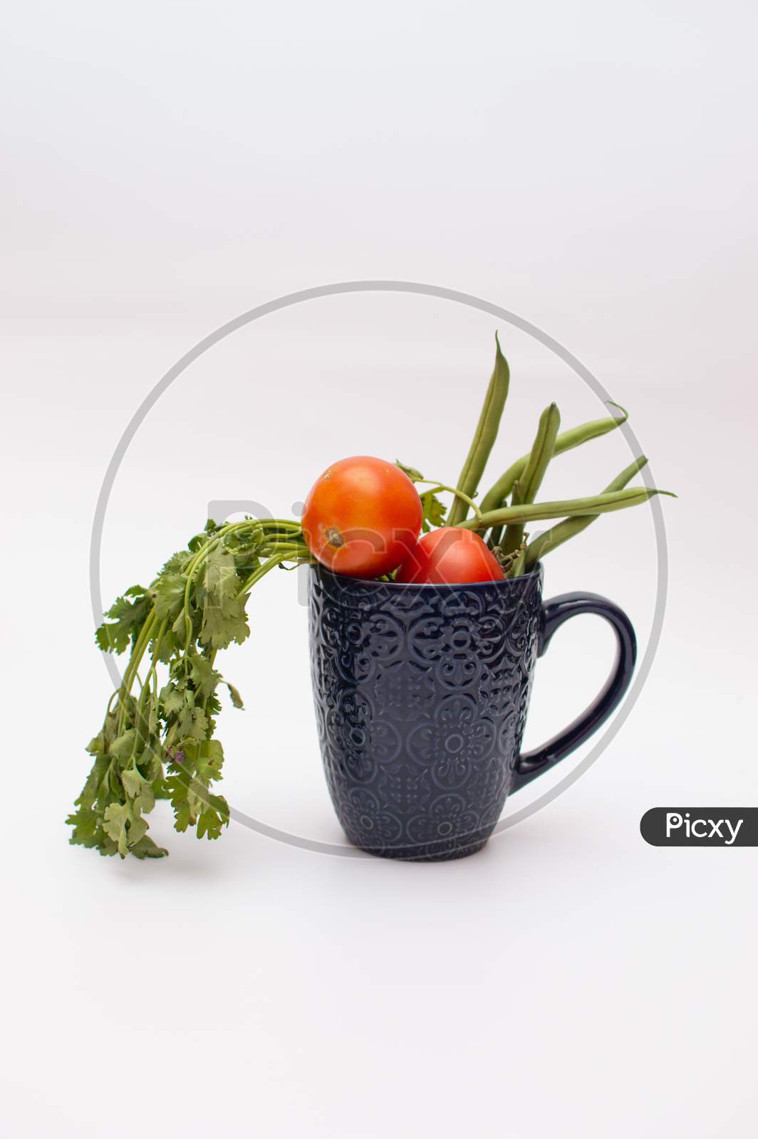 Vegetables and fruit in a blue mug on white background