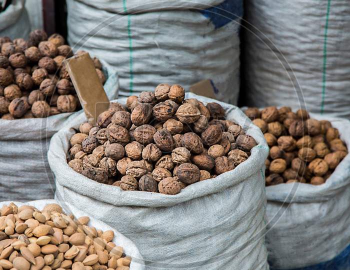 Walnuts And Pistachios For Sale At Market In White Sacks , Variety Of Dry Fruits Displayed Outside The Shop - Image
