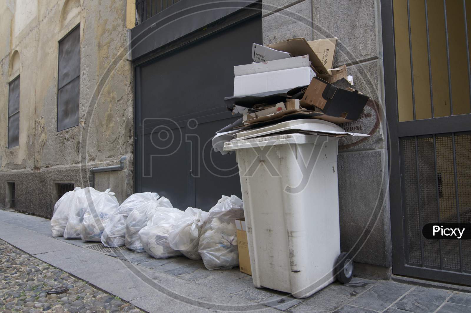 Cardboard Filled Trash Container And Rubbish Bags On The Streets