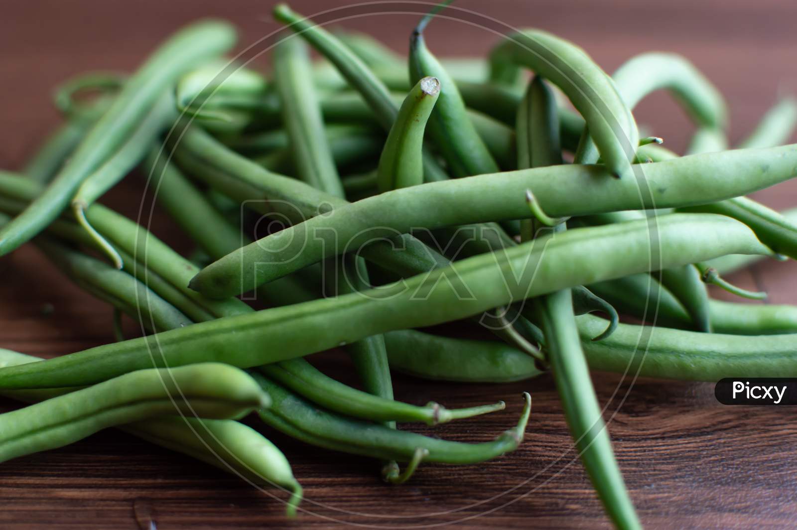 Bunch of green beans on a brown wooden floor