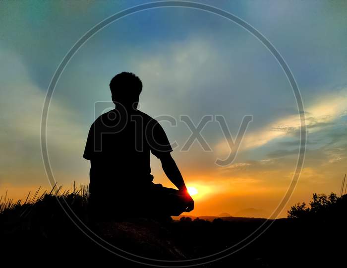 A man sitting on a hill and enjoy the sunset